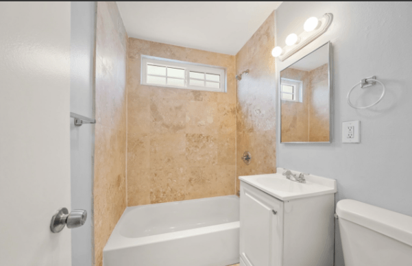 A bathroom with a white tub, sink, and toilet.